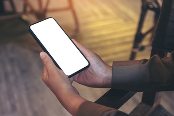 Mockup image of hands holding black mobile phone with blank white desktop screen
