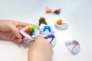 Colorful orthodontic appliances hands on white background