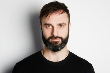 Fototapeta premium Portrait of bearded man in black tshirt on the empty background.