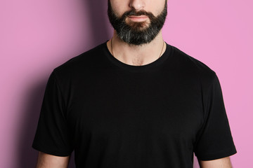 Portrait of bearded man in black tshirt on the empty pink background.