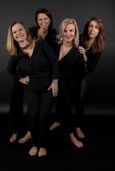 Four friends posing in a studio with a black background