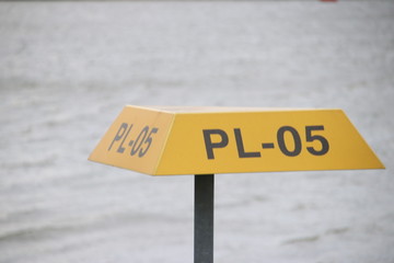 Yellow triangle warning signs above underground pipeline with tag number on it in the port of...