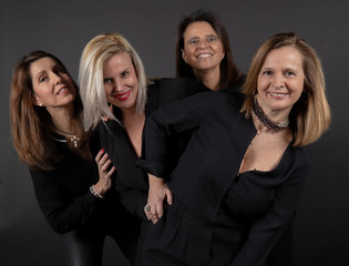 Four friends posing in a studio with a black background