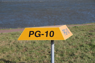 Yellow triangle warning signs above underground pipeline with tag number on it in the port of...