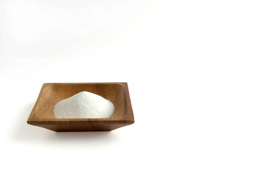横長で白い背景の左にある正方形の木の器に盛られている白い塩