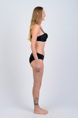 Fototapeta premium Full body shot profile view of happy blonde woman in bikini smiling