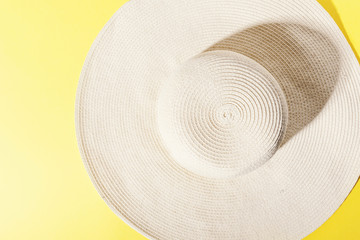 Fototapeta na wymiar Straw hat on bright yellow sunny background