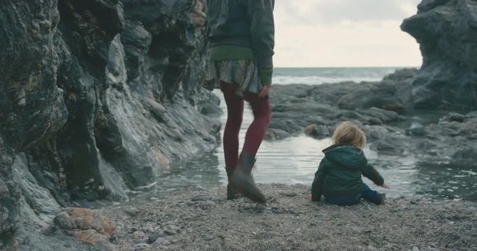 Mother and toddler sitting on the beach in winter