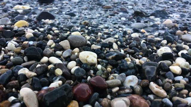 stones on the beach, waves splashing water on colorful pebbles on the beach