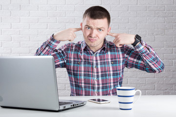 Businessman in his office covering his ears