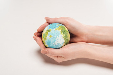cropped view of woman holding earth model on white background, global warming concept