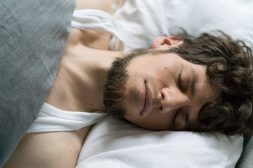 Fototapeta na wymiar Cute handsome young man sleeping on bed.