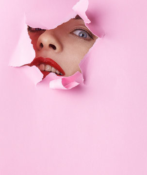 Fashion Close Up Minimalistic Portrait. Woman Face With Red Lips And Perfect Skin In Pink Paper Hole Background