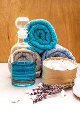 Obraz na płótnie Canvas Spa concept, natural ingredients. Bath towels, sea salt with lavender, shower gel, brush. On a stone and wooden background