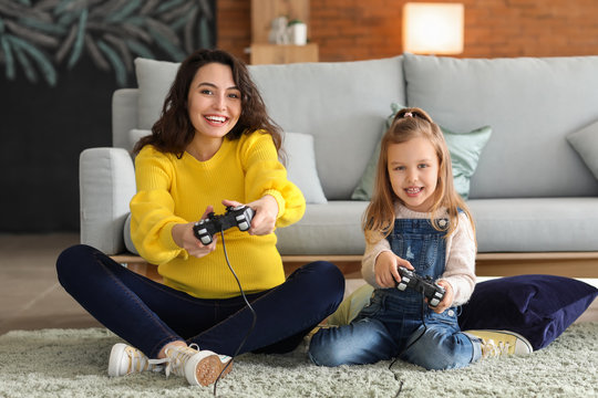 Pregnant Mother With Little Daughter Playing Video Games At Home