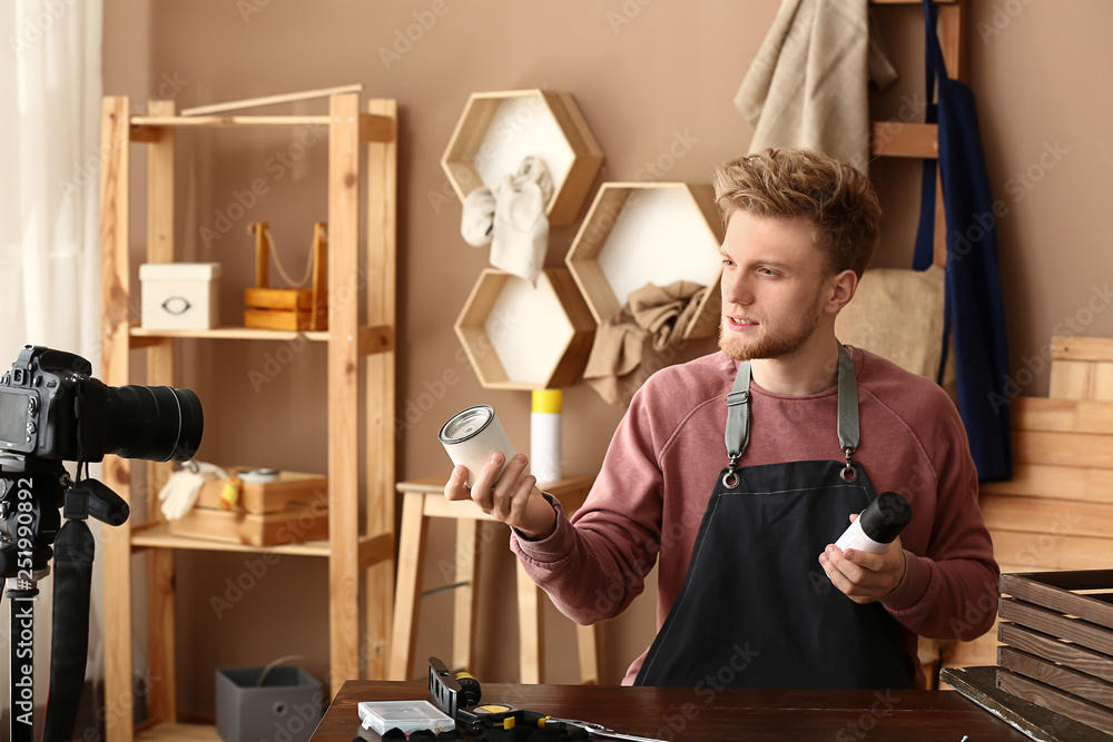 Wall mural Young male blogger recording video in workshop