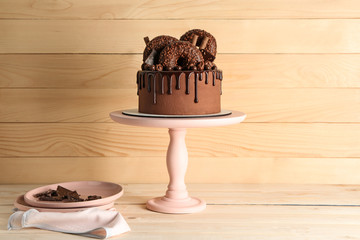 Stand with sweet chocolate cake on wooden table