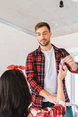 handsome man standing on ladder and taking light bulb while looking at girlfriend