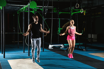Young sporty couple jumping a rope in gym