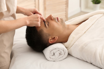 Fototapeta na wymiar Man receiving face massage in beauty salon