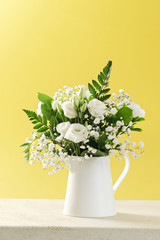 Flowers in a vase on marble table and yellow background with  space for text.