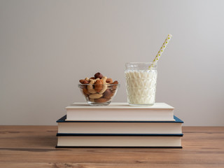 Bücherstapel mit einem Glas Milch und einer Schale Nüsse