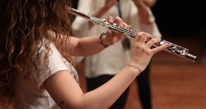 young woman playing flute, clarinet, classical music concert
