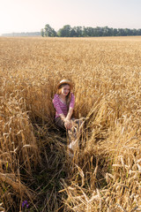 Naklejka na ściany i meble Portrait of a girl sitting in wheat.
