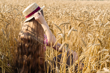 A girl with very long hair. sits in wheat.