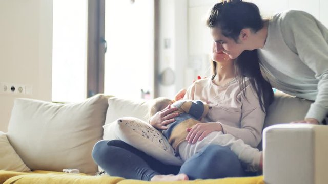 Breastfeeding baby. Young parents look at their newborn child and kissing