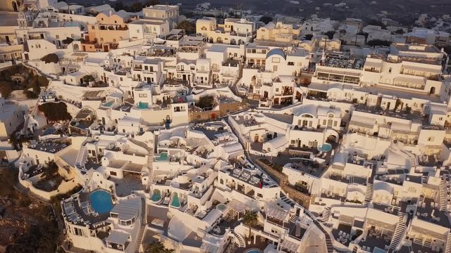 Flight over traditional terraced white villas in Fira (Thira) town at sunset, Santorini, Greece