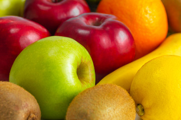 red green apples with ripe bananas and kiwi orange lemon on a white background