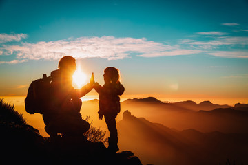 father and little daughter enjoy travel in mountains at sunset - obrazy, fototapety, plakaty