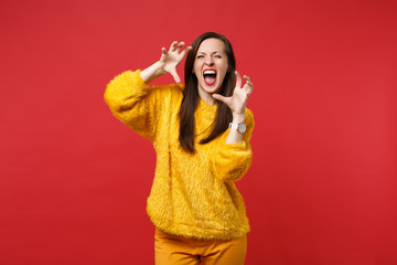 Crazy young woman in yellow fur sweater shouting, growling like animal, making cat claws gesture...