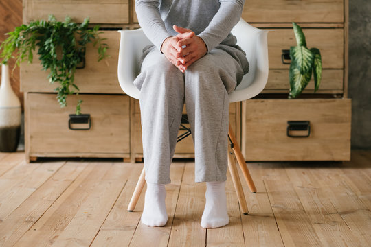 Morning doubts. Man in pyjamas sitting in chair tiptoed and with steepling hands.