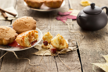 Muffins with jam on wooden background. Pouring jam on a cupcake.