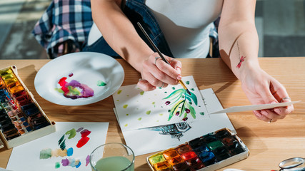 Artist workplace with drafts and palette supplies around. Painter doing sketch brushstrokes getting...