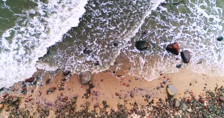 Rocky beach and sea waves hitting seashore from top view. Wild nature, stormy weather.