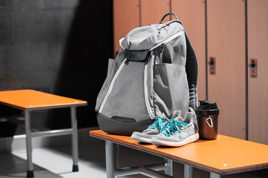 Sports shoes, sport backpack and sport water bottle in gym locker room.