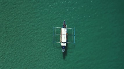 Aerial shot of a filipino banca boat floating in turquoise pristine water. Palawan Island, Philippines