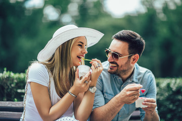 Couple joking and having fun while eating an ice cream in the park.