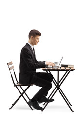 Young man in a suit sitting at a coffee table and working on a laptop