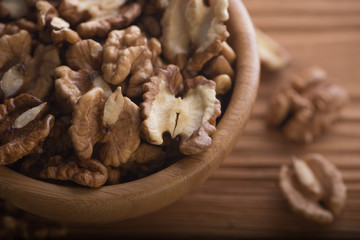 Top close up view of group of large dried ukranian russian peeled Walnut kernels in a bowl on rustic wooden background