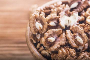 Top close up view of group of large dried ukranian russian peeled Walnut kernels in a bowl on rustic wooden background