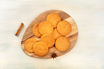 Ginger biscuits on a wooden tray, shot from the top with cinnamon, anise, and a place for text