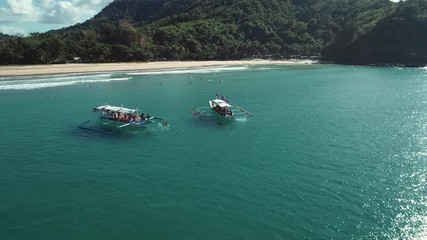 Aerial shot of a two filipino touristic boats floating in turquoise pristine water. Palawan Island, Philippines