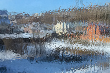 Blurred background: translucent frozen glass in winter with small cracks. View of the suburb