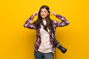 Photographer teenager girl over yellow wall having doubts and thinking