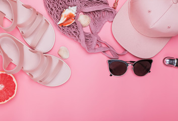 Pink sandals and cap, shopping bag and sunglasses on the pink background