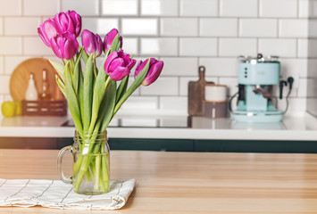 Purple tulips in a glass jar standing on the modern kitchen